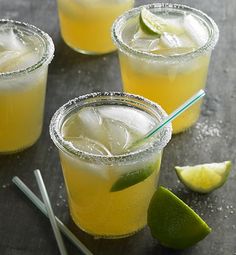 three glasses filled with lemonade and limes