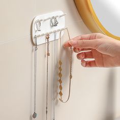 a person is trying to put some jewelry on a wall mounted necklace holder that holds several pairs of earrings