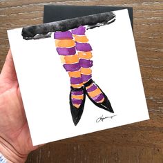 a hand holding up a card with an image of a woman's legs in purple and orange striped stockings