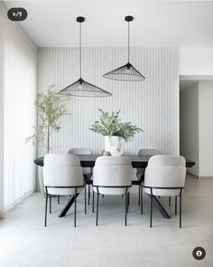 a dining room table with four chairs and a potted plant