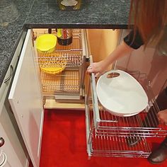 a woman is opening the dishwasher door to clean it up in the kitchen