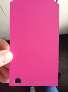 a person holding up a pink card in their hand