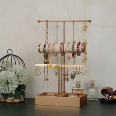 a jewelry rack with various bracelets and rings on it next to a potted plant