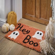 a door mat that says hey boo on it next to two balls and a broom