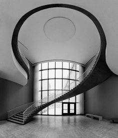 an empty room with stairs leading up to the second floor and large windows on either side