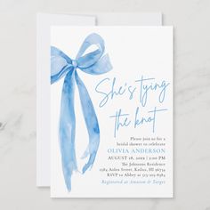 this is an image of a blue watercolor bow birthday party card with the words she's tying the knot on it