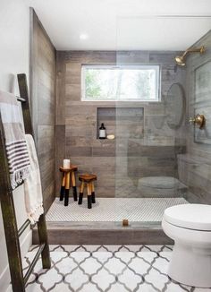 a white toilet sitting in a bathroom next to a walk in shower and wooden ladder