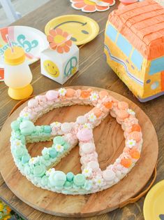 a peace sign cake sitting on top of a wooden table next to plates and cups