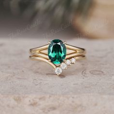 an emerald colored ring with three white diamonds on the bottom and one green stone in the middle