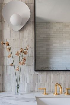 a bathroom with marble counter tops and gold faucets in front of a mirror