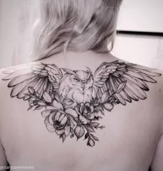 the back of a woman's shoulder with an owl and flowers tattoo on it