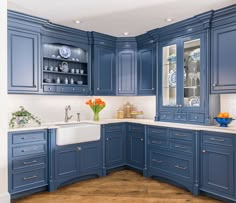 a large kitchen with blue cabinets and white counter tops is shown in this image, there are vases on the cabinet doors