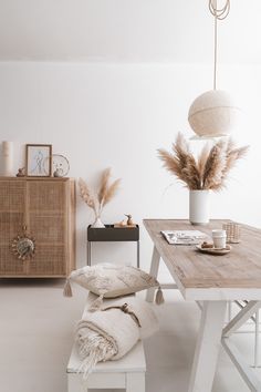 a white room with a wooden table and some pillows on the floor next to it