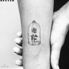 a rose in a glass bottle tattoo on the left inner arm