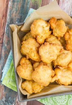 some fried food is in a bowl on a wooden table with a napkin and fork