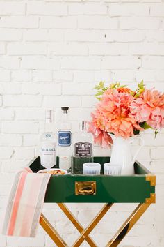 a green tray with flowers and personal care products on it next to a white brick wall