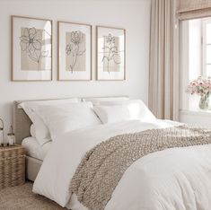 a bed with white sheets and pillows in a bedroom next to two pictures on the wall