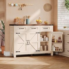 a kitchen with white cupboards and wooden flooring in front of a brick wall