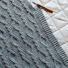 a crocheted blanket laying on top of a bed next to a wooden pen