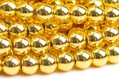 gold beads are arranged in rows on a white background