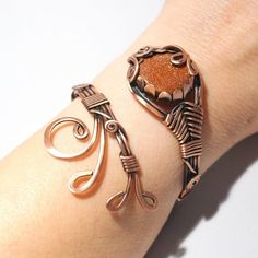 a woman's arm with two bracelets on it and an orange stone in the middle