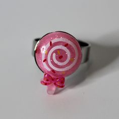 a pink lollipop ring with sprinkles and a bow on it