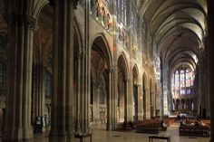 the inside of a large cathedral with stained glass windows and pews on both sides