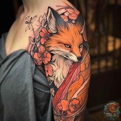 a woman's arm with an orange fox and flowers tattoo on her left shoulder