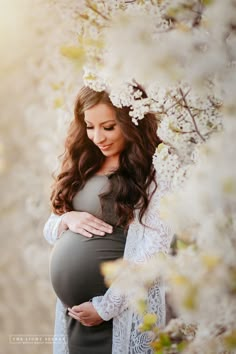 a pregnant woman standing in front of a tree