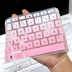 a hand holding a pink and white keyboard