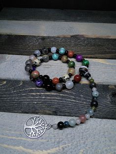 This is a beautiful re-imagined rosary based on the classic Catholic rosary. The beads are natural stone- green imperial jasper, purple imperial jasper, agate, goldstone, turquoise, unakite, fancy jasper, brown banded agate, jet, dalmatian stone, and kiwi stone. There are three decades of nine beads each. The center is a brown banded agate, and I have capped it off with a tree of life. With this rosary I'm including a simple chant which has resonated with me, but feel free to use your own! Pagan Spiritual Rosary With Round Beads For Meditation, Spiritual Rosary For Meditation With Round Beads, Spiritual Gemstone Beads Rosary, Bohemian Hand-strung Healing Rosary, Bohemian Hand-strung Rosary For Healing, Spiritual Rosary With 8mm Beads, Spiritual Hand-strung Rosary For Meditation, Spiritual Green Hand Wrapped Beads, Spiritual Beaded Rosary For Jewelry Making