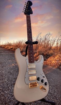 an electric guitar sitting on top of a stand in the middle of a gravel road