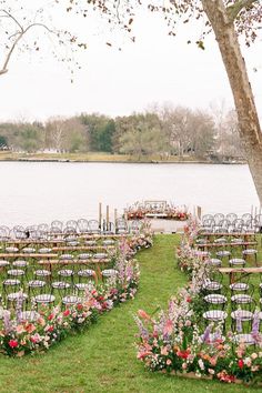 an outdoor wedding set up with chairs and flowers on the grass by the water's edge