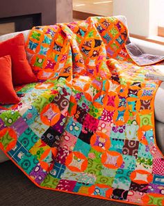 an orange and multicolored quilt on a couch