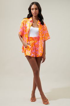 Brb, off to somewhere tropical with a drink in hand. The ideal vacation button up is here. A bright pink and orange tropical print decorates the Otto shirt. A classic collared top with a functional button front. It maintains a relaxed boyfriend fit and can easily be paired with your favorite bottoms or make it a set with the matching shorts.- Satin- Boyfriend fit- Pockets- Functional buttons- Color: Orange MultiSize + Fit - Model is 5'10" and wearing size XS- Measurements taken from size S - Che Spring Tropical Button-up Top, Summer Button-up Top With Tropical Print, Vibrant Print Button-up Tops For Vacation, Hawian Shirt, Vacation Button-up Shirt With Vibrant Print, Tropical Multicolor Button-up Shirt, Collared Top, Bra Dress, Body Dress