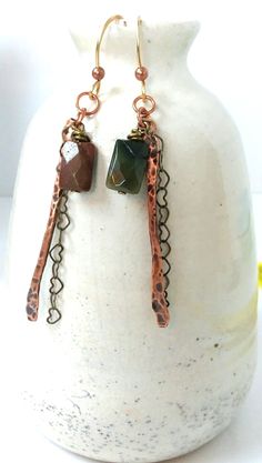 These long copper earrings are made from several materials.  They have a 2" solid copper, hammered bar with a dainty bronze, heart chain hanging beside it. The 1cm rectangle stones are faceted and different colors.  These are Jasper-One green, one reddish brown These are 3" long, lightweight with handcrafted brass French ear wires. We have these and many other handcrafted jewelry items in our store. Please look around for a unique gift idea If you need any further information, please contact me. Rustic Handmade Metal Jewelry, Rustic Drop Earrings Jewelry For Gift, Rustic Drop Earrings Jewelry Gift, Rustic Drop Earrings As A Gift, Rustic Dangle Earrings As A Gift, Rustic Dangle Earrings For Gift, Rustic Green Dangle Jewelry, Rustic Nickel-free Dangle Jewelry, Green Rustic Dangle Jewelry