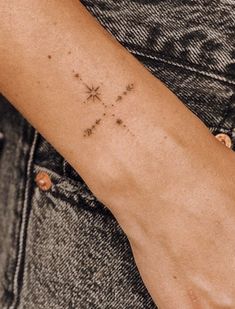 a woman's arm with a small cross tattoo on the left side of her arm