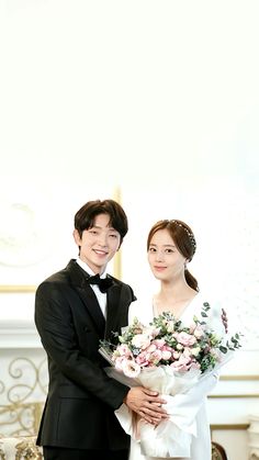 a man and woman standing next to each other in formal wear, holding bouquets