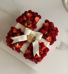 a heart shaped cake with strawberries on top and a white ribbon around the edges