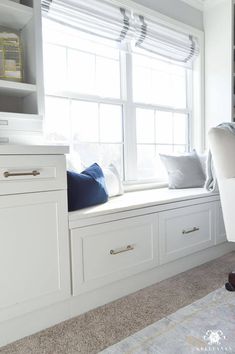 a window seat in the corner of a room with bookshelves and pillows on it