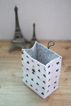 a small white bag sitting on top of a wooden table next to the eiffel tower