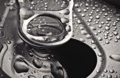 water drops on the surface of a metal bowl with an open lid and drain in the center