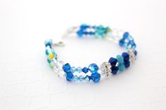 "Gorgeous handmade crystal bracelet perfect for a special occasion. This beautiful bracelet is made of different shades of blue, turquoise and clear Swarovski and Czech Crystals separated by silver rhinestone bars on beading wire then finished with a silver clasp. Please choose how many rows you want. The Bracelet will ship to fit a 6 1/2 inch wrist, unless you specify a different size. Contact me if you need to order more for your bridal party. Please see last picture for matching jewelry avail Blue Beaded Bracelets For Weddings, Blue Round Bead Bracelets For Weddings, Blue Round Beads Bracelet For Wedding, Adjustable Blue Beaded Bracelets For Wedding, Adjustable Turquoise Crystal Bracelets, Blue Faceted Beads Jewelry For Wedding, Blue Crystal Bracelets For Wedding, Adjustable Blue Crystal Bracelet For Wedding, Handmade Blue Crystal Bracelet