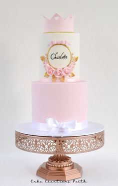 a three tiered cake with pink frosting and gold trimmings on top