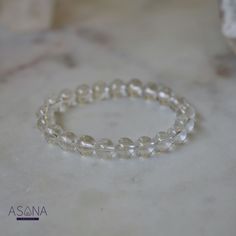 Introducing Asana Crystals' Clear Quartz Bracelet—a timeless and versatile accessory that embodies clarity, purity, and positive energy. Handcrafted from natural Clear Quartz, each bead in this bracelet exudes a pristine transparency symbolizing clarity of mind and spirit. Known as the "master healer," Clear Quartz amplifies energy, enhances intuition, and promotes overall well-being. Featuring smooth, round beads measuring 8mm, this bracelet offers a classic elegance suitable for any style or occasion. With no closure, the beaded stretch design ensures effortless wearability and comfort, allowing you to carry the uplifting energy of Clear Quartz throughout your day. Embrace the pure and transformative energy of Clear Quartz and elevate your look with Asana Crystals' Clear Quartz Bracelet— Minimalist Crystal Bracelet With Round Beads For Healing, Minimalist Round Beads Crystal Bracelet For Healing, Minimalist Crystal Bracelet With Round Beads For Everyday, Adjustable Clear Round Bead Crystals, Minimalist Everyday Crystal Bracelet With Round Beads, Everyday Hypoallergenic Crystal Bracelet With Round Beads, Minimalist Round Bead Crystal Bracelet For Everyday, Elegant Crystal Bracelet For Meditation, Elegant Hand-strung Crystal Bracelet For Meditation