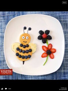 a white plate topped with fruit and a bee cut in to the shape of flowers