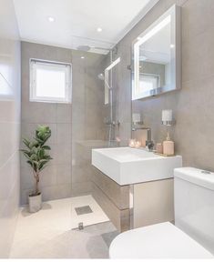 a white toilet sitting next to a sink in a bathroom under a mirror and lights