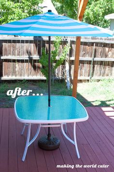 an umbrella sitting on top of a table in the middle of a wooden deck next to a fence