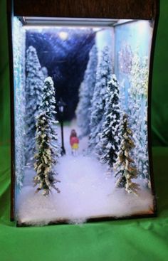 a snow scene with trees and a person in the distance under a street light on a green background