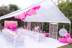 a party tent set up with tables and chairs for an outdoor event, decorated with pink balloons